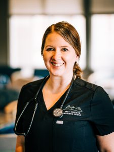 Portrait of nurse smiling in black scrubs with East Cascade Womens Group logo on scrubs and stethoscope around neck.